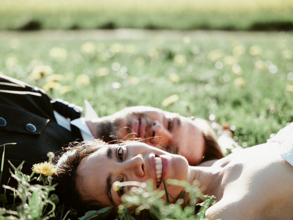 Brautpaar liegt im Gras und schaut in die Kamera